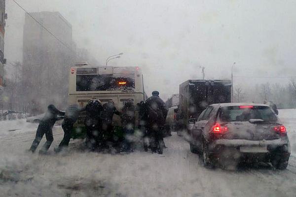 Mọi người cùng đẩy một chiếc ôtô bị kẹt trong bão tuyết.