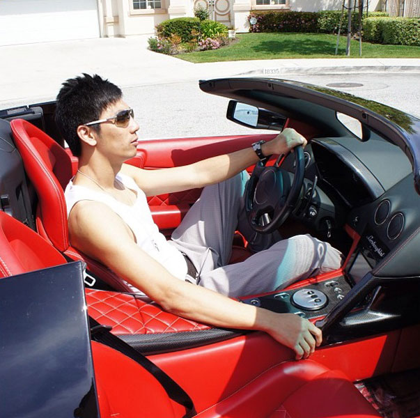 Robert ngồi trong một chiếc siêu xe Lamborghini mui trần với nội thất đỏ rực.