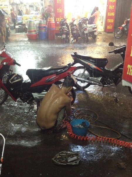 Người thợ dầm mưa, sửa xe cho khách. Ảnh: Toi Nguyen/Otofun