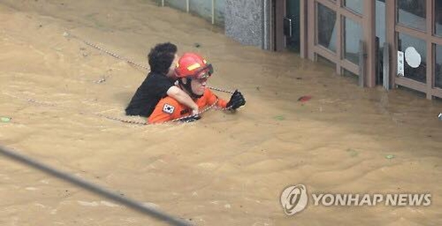 
Lực lượng cứu hộ đang di dời một người dân ra vùng lũ lụt.
