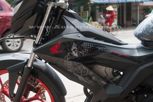 
Để tạo cá tính trên nền sơn đen nhám các chi tiết như logo cánh chim của Honda hay bộ tem của xe xuất hiện trong màu đỏ và trắng bắt mắt.
