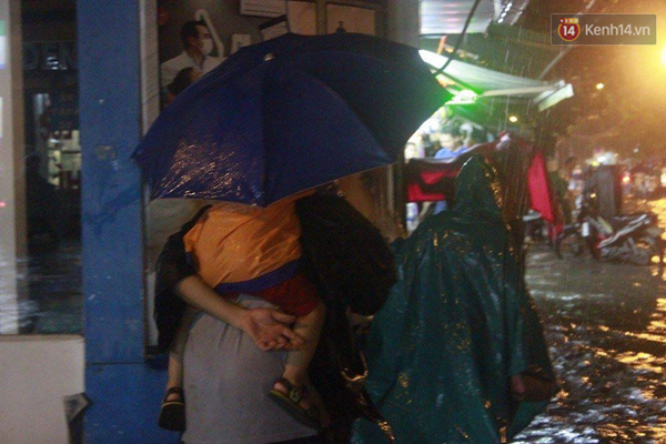 
Người dân đứng trú tạm ở các quán xá bên đường chờ cơn mưa tan. Ảnh: Toàn Nguyễn.

