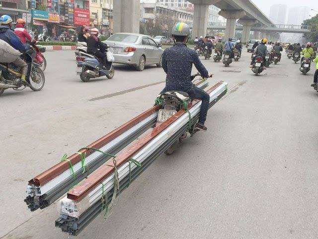 Nam thanh niên dùng xe máy trở hàng chục tấm thép di chuyển trên đường phố Hà Nội. Ảnh: Facebook Lương Thế Huy.