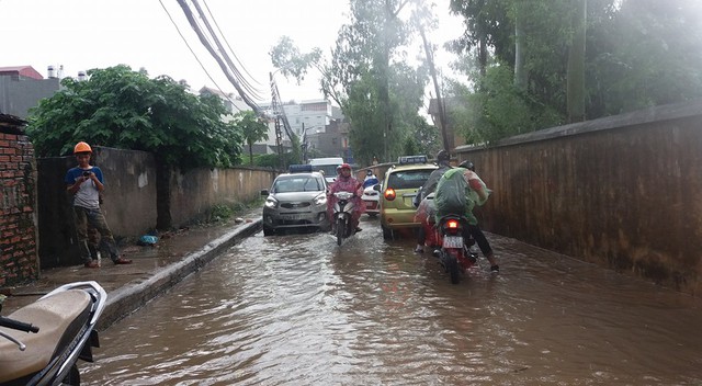 
Phố Thịnh Liệt thuộc quận Hoàng Mai bị ngập vì mưa rào khiến người dân đi lại gặp nhiều khó khăn. Ảnh: Thelong Nguyen
