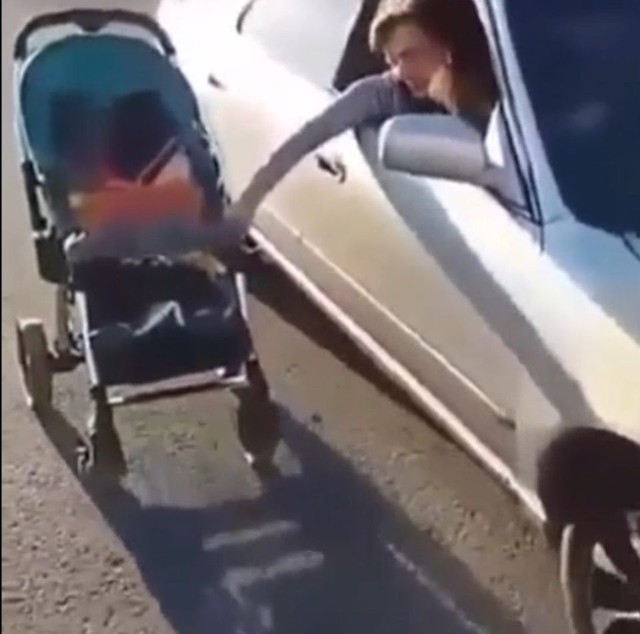 
Bà mẹ vừa lái ô tô vừa thò tay ra ngoài đẩy xe nôi cho con trai. Ảnh cắt từ video
