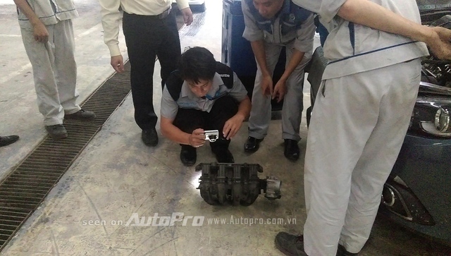 Ông Ykomoto đang chụp lại hiện vật của chiếc xe Mazda 3 có vấn đề đèn check engine tại Việt Nam.