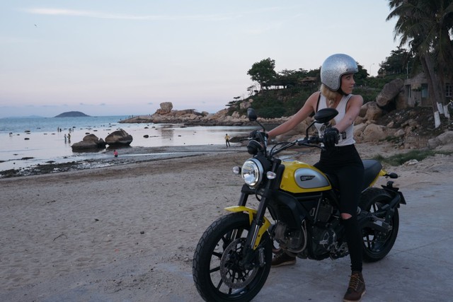 Laura Heidenreich ngồi trên chiếc Ducati Scrambler tại bãi biển Nha Trang.