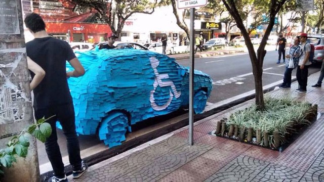 Chiếc ô tô đỗ lên chỗ dành cho người khuyết tật bị dán kín giấy nhớ màu xanh. Nổi bật trên nền xanh là biểu tượng của người khuyết tật như một lời nhắc nhở cho người đỗ xe.
