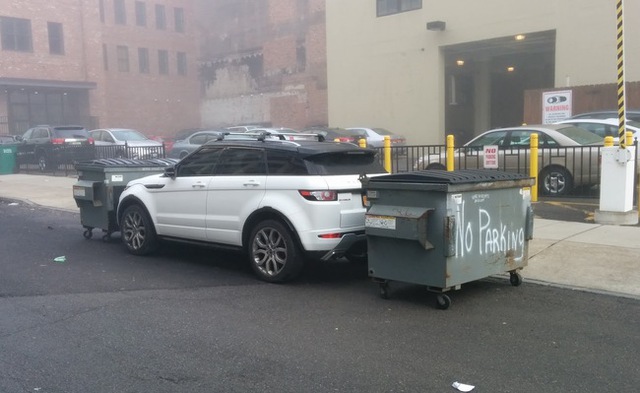 Dùng thùng rác chặn hai đầu cho chiếc Range Rover Evoque màu trắng không có đường thoát. Trên thùng rác còn có dòng chữ “cấm đỗ xe” sơn màu trắng.