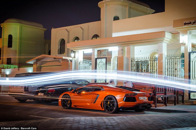 Siêu xe Lamborghini Aventador màu cam nằm yên trên đường phố Qatar về đêm.