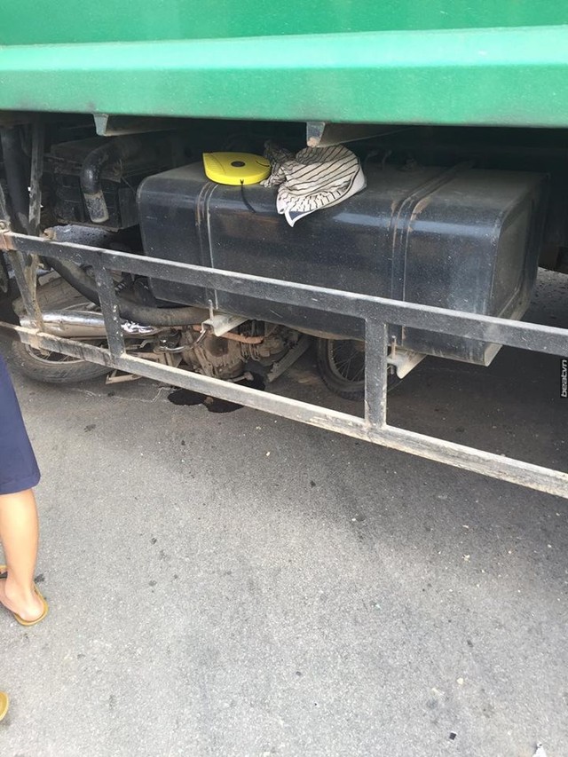 Một xe máy bị cuốn vào gầm xe rác