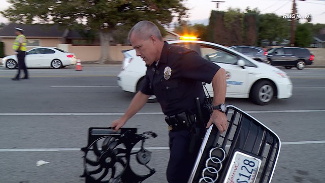 
Một cảnh sát xách lưới tản nhiệt và quạt rơi ra từ chiếc sedan Audi.

