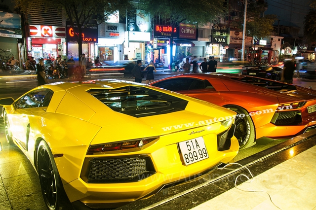 
Lamborghini Aventador LP700-4 màu vàng và cam thường xuyên xuất hiện cùng nhau vào mỗi dịp cuối tuần và đến ngày vui trọng đại của Minh Nhựa hai đại gia này thay nhau thi triển màn nẹt pô khá phấn khích. Theo đại gia Trung Cao chủ nhân của chiếc Aventador màu cam, anh tính đem thêm chiếc Murcielago LP640 màu vàng đến trưng bày nhưng chủ nhân bữa tiệc lại nói khéo hết chỗ để sắp xếp xe.

