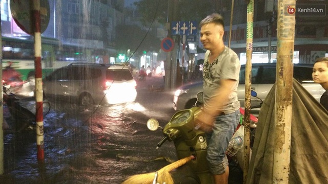 
Người dân trên đường Điện Biên Phủ phải chạy ra trước nhà chỉ dẫn người tham gia giao thông tránh né những nơi có hố sụp và gờ chạy lên vỉa hè vì mưa quá lớn không chạy được. Ảnh: Lê Giang.
