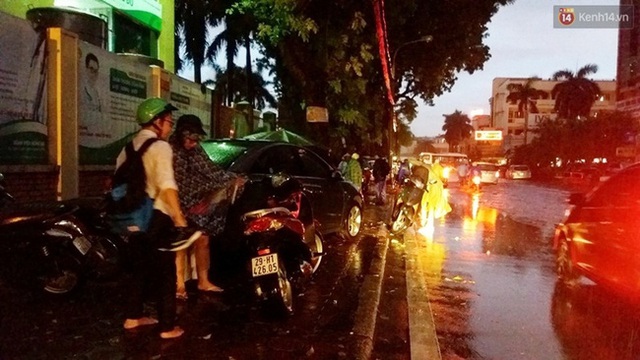 Một số phụ huynh đón con đi học về cũng dừng lại ở vỉa hè tránh mưa. Ảnh: Thế Long