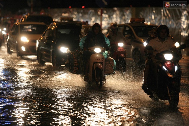 
Nam thanh niên chở hàng hóa cồng kềnh đi trong cơn mưa. Ảnh: Mai Lân
