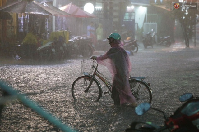 
Cụ già dắt xe đạp đi giữa cơn mưa vì sợ bị ngã. Ảnh: Tứ Quý
