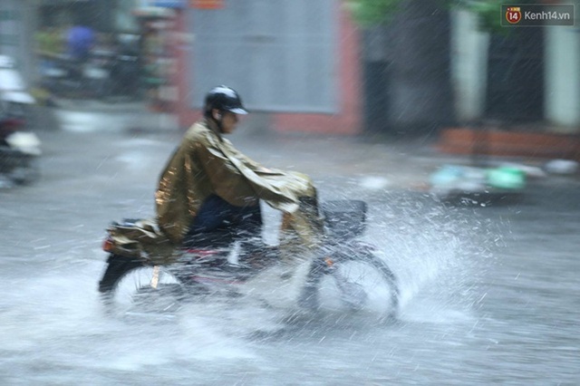 
Nhiều người phải gác chân lên xe để tránh ướt. Ảnh: Đại Thế Nguyễn
