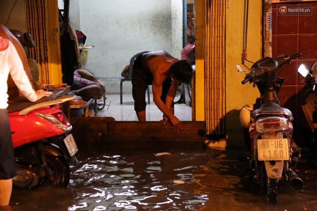 Đường ngập cao hơn 1m khiến nước tràn vào nhà, người dân phải dùng ván che chắn.