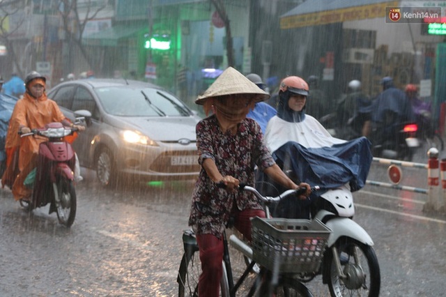 
Người phụ nữ đội nón lá dầm mình trong mưa lớn
