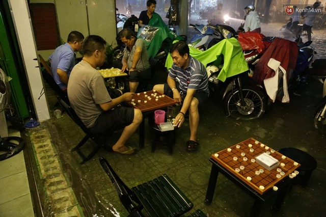 
Nhiều người trú mưa ở quán cafe và tranh thủ chơi cờ. Ảnh: Lê Giang
