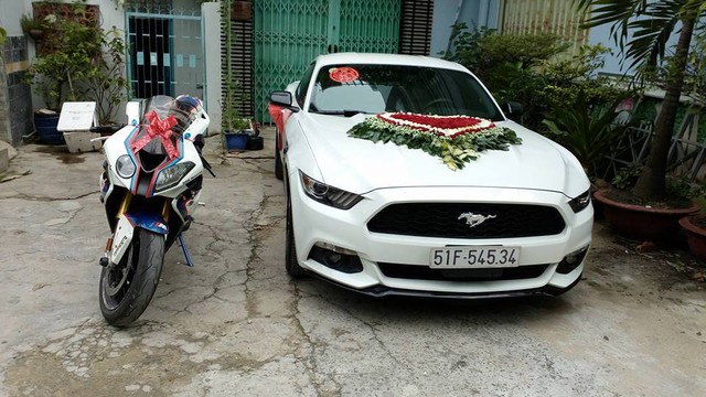 
Chiếc xe thể thao có giá 2 tỷ Đồng tại thị trường Việt Nam được kết hoa cưới cỡ lớn trước nắp capô, ngoài ra, hai bên tay nắm cửa xe còn được trang trí nơ cưới đẹp mắt. Trong ảnh, Ford Mustang thế hệ thứ 6 đọ dáng cùng BMW S1000RR.
