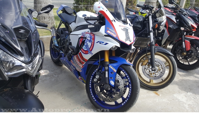 
Có bộ áo nổi bật không kém siêu mô tô tiền tỷ Kawasaki Ninja H2 là chiếc sport bike đang khá được ưa chuộng tại thị trường Việt Nam, Yamaha YZF-R1. Mẫu xe phân khối lớn được chủ nhân cho lên bộ áo với hai tông màu chủ tạo là trắng-xanh đậm. Điểm nhấn là bộ tem màu đỏ và vành xe được sơn màu xanh bắt mắt.
