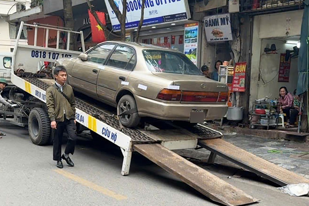 Cẩu, kéo chiếc ô tô phủ bạt, bị 'bỏ quên' nhiều năm trên phố Bát Sứ- Ảnh 2.