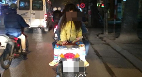 Hình ảnh bà mẹ đèo con ngồi ngược, đầu không đội mũ bảo hiểm được chụp trên phố Hà Nội vào buổi tối