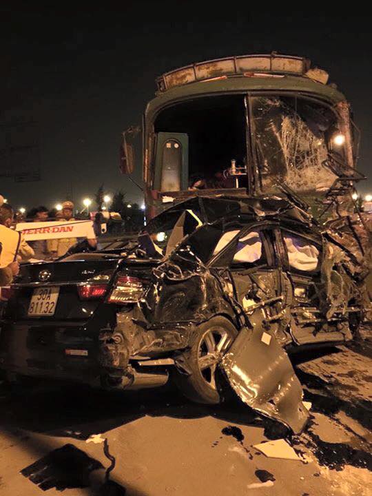 Xe Toyota Camry bị kéo lên biến dạng hoàn toàn. Xe khách cũ cũng tan nát phần đầu.