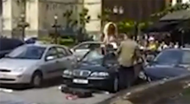 
Cô gái leo lên nóc xe và dùng đàn guitar để đập vỡ kính xe sang BMW của bạn trai. Ảnh cắt từ video
