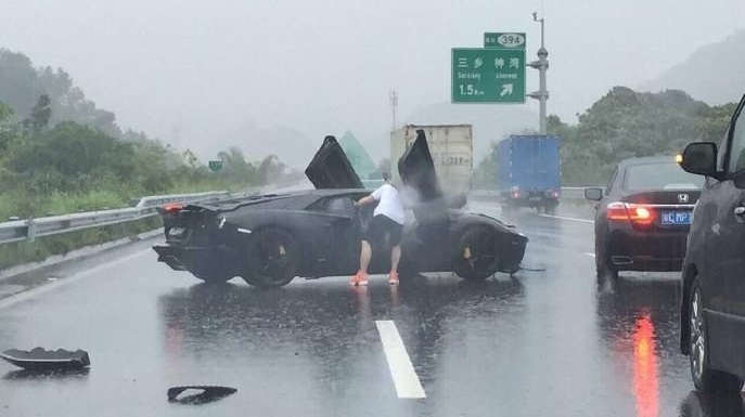 
Nam thanh niên cầm lái chiếc Lamborghini Aventador cúi tìm đồ trong xe sau vụ tai nạn.
