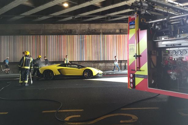 
Chiếc Lamborghini mui trần bốc cháy trên con đường dưới gầm cầu.
