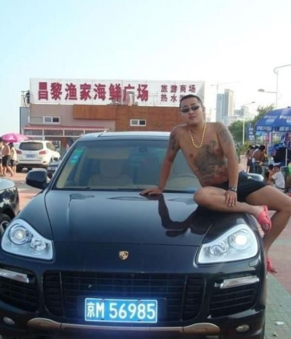 
G&atilde; gangster tr&egrave;o l&ecirc;n đầu xe Porsche Cayenne.
