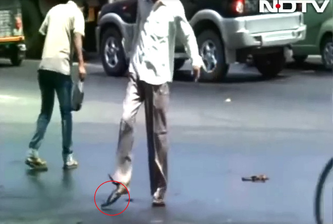 
Một người đàn ông bị đứt quai dép khi đi trên đường chảy nhựa. Ảnh cắt từ video
