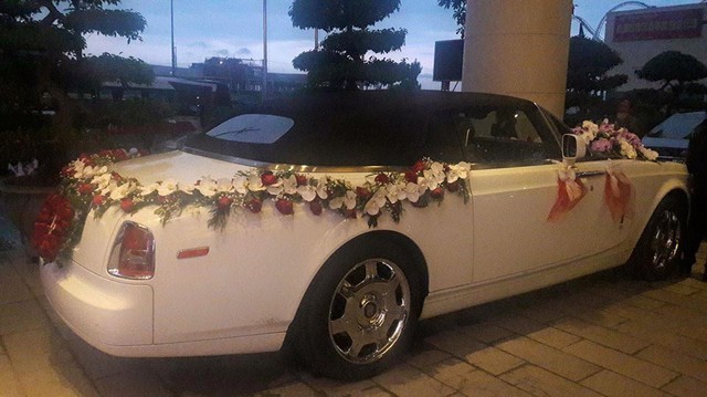
Hoa cưới được trang trí khắp thân chiếc xe quý tộc Anh Quốc. Tại thị trường Việt Nam, Phantom Drophead Coupe có số lượng vào khoảng 8 chiếc cùng mức giá hơn 1 triệu đô khi nộp đầy đủ tất cả các loại thuế.
