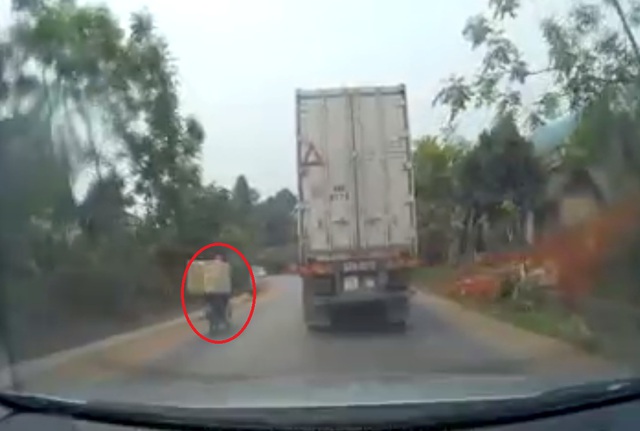 
Nam thanh niên lái xe máy chở hàng vượt lên xe container. Ảnh cắt từ video
