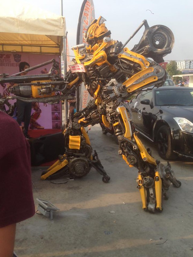 Bên cạnh đó là chú robot gợi liên tưởng đến Bumblebee trong phim Transformers đứng cạnh chiếc xe thể thao Nissan 350Z màu đen.