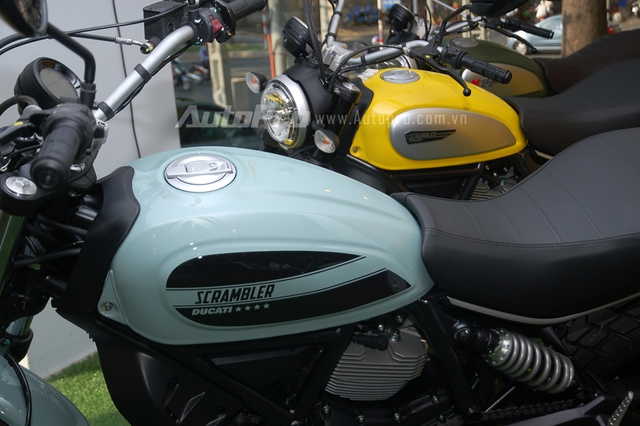 So với đàn anh 800 phân khối màu vàng đứng bên cạnh, Ducati Scrambler Sixty2 có thiết kế không thay đổi nhiều. Điểm khác biệt nằm ở ốp bình xăng với 2 sọc đen cỡ lớn cùng dòng chữ Scrambler nằm chính giữa, giúp mẫu mô tô 400 phân khối thu hút nhiều ánh nhìn.