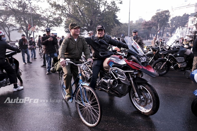 
Một biker trên chiếc BMW R1200 tạo dáng cạnh một người trung niên có trang phục và chiếc xe đạp mang phong cách cựu chiến binh.
