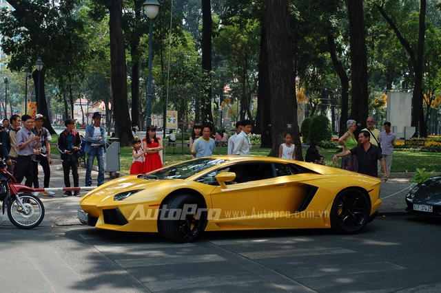 
Mọi người vây quanh chiếc siêu xe Lamborghini Aventador màu vàng rực rỡ.
