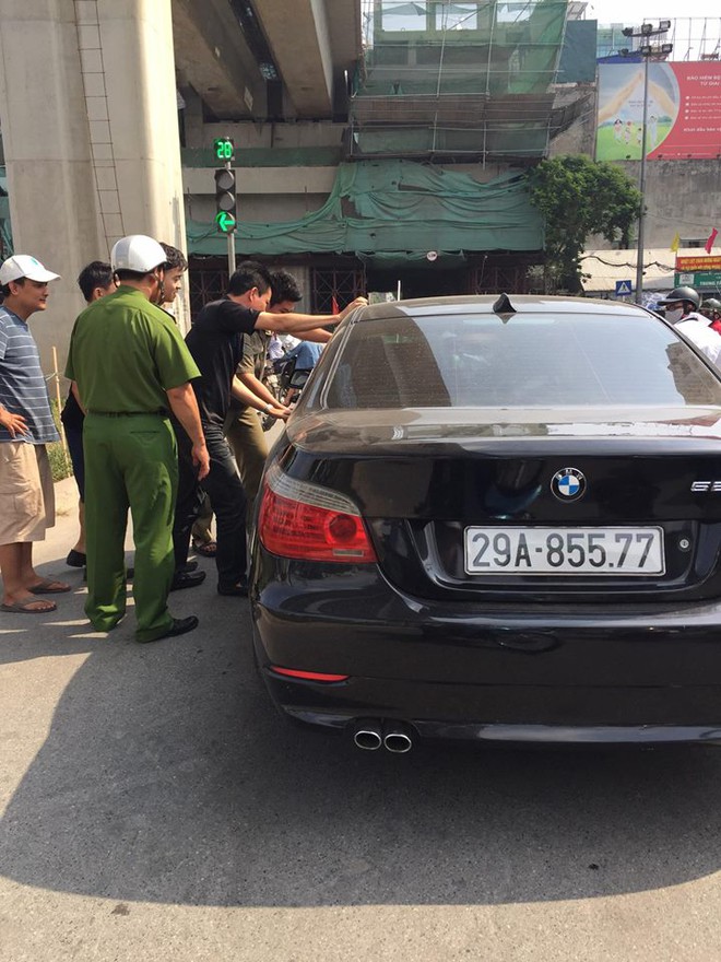 
Người dân và lực lượng chức năng vây quanh chiếc BMW.
