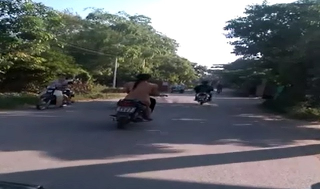 Một cô gái khỏa thân chạy xe máy trên phố đông người.  Hình ảnh cắt từ video