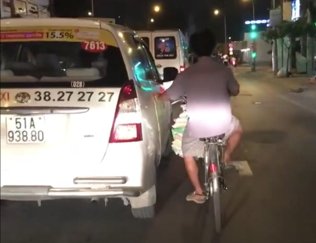 Tp.HCM: Người đàn ông thản nhiên bám xe taxi đi suốt một đoạn đường dài vì lười đạp xe - Ảnh 1.
