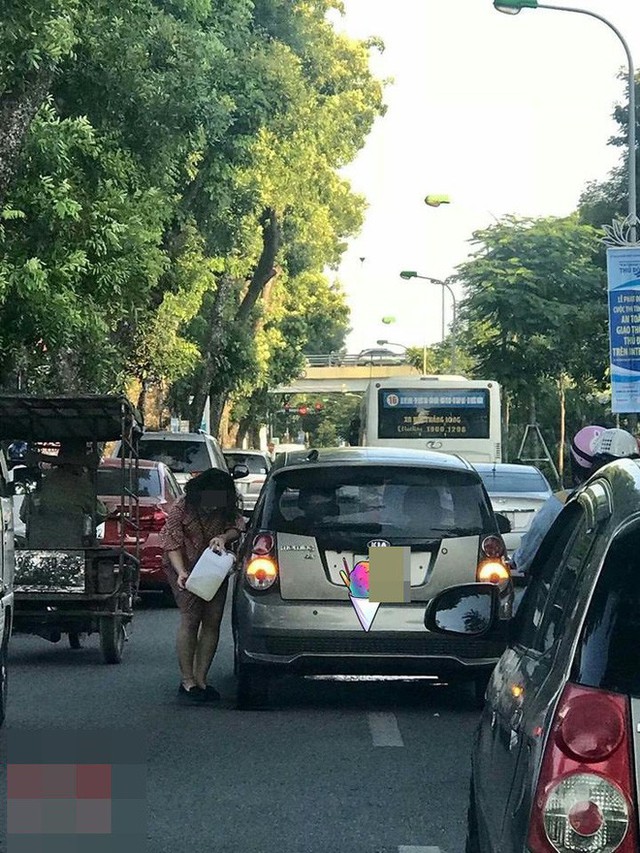  Tranh thủ đường đông, người phụ nữ cầm can xăng đổ cho ô tô ngay giữa phố Hà Nội - Ảnh 1.