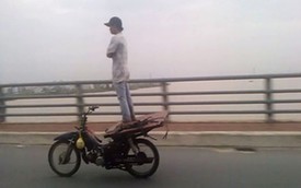 Thanh niên Việt khoanh tay, đứng trên yên xe máy đang chạy