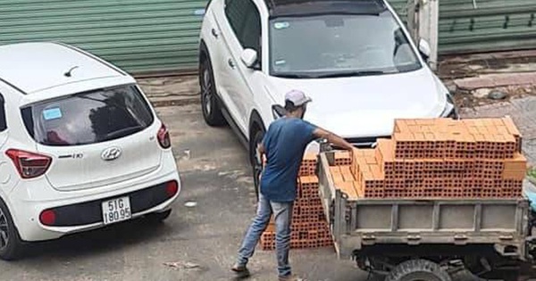The man used a truck to carry bricks, lined up to block 2 cars parked in front of the house